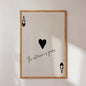 Framed artwork with playing card symbols and text on a white wall