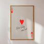 Framed artwork with red hearts and text on a white wall