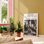 Living room with plants, a coffee table, and a framed newspaper on a yellow wall.