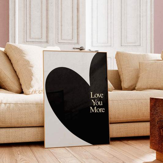 Heart-shaped artwork with 'Love You More' text in a living room setting.