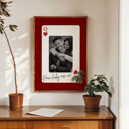 Custom photo playing card wall art displayed above wooden cabinet with plants